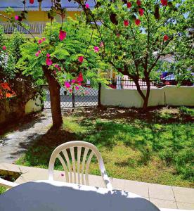 a table and a white chair and a tree with pink flowers at Maisonette with Garden& Parking Polichrono in Polychrono