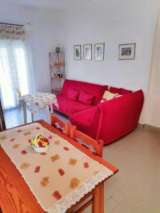 a living room with a red couch and a table at Maisonette with Garden& Parking Polichrono in Polychrono