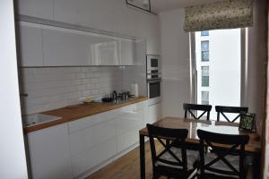 a kitchen with white cabinets and a table and chairs at Klara - Harmonia Oliwska in Gdańsk
