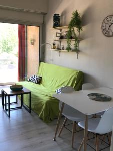 ein Wohnzimmer mit einem grünen Sofa und einem Tisch in der Unterkunft Duplex rénové les pieds dans l'eau in Calvi