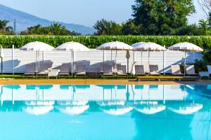 una piscina con sedie e ombrelloni accanto a un edificio di Resort & Winery Bosco De Medici a Pompei