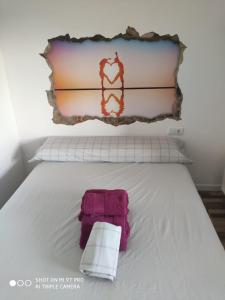 Una cama blanca con una toalla rosa. en La Burbuja, en Almería