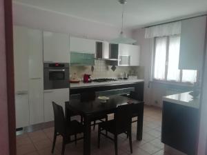a kitchen with a table and chairs and a kitchen with white cabinets at casa papillon in Sestino