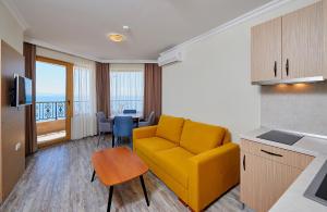 a living room with a yellow couch and a table at Crotiria Beach - Aparthotel in Pomorie