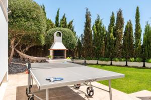 a ping pong table in a garden with a fireplace at Villa Orquidea in Son Bou