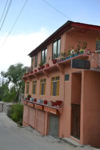 ein rosafarbenes Gebäude mit Pflanzen auf dem Balkon in der Unterkunft High Cliff Guest House in Khapalu