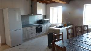 a kitchen with a white refrigerator and a table at Maison de la Delle in Pertheville-Ners