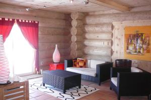 a living room with wooden walls with a couch and chairs at Auberge Couleurs de France in Lac-Simon