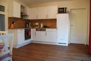 a kitchen with white cabinets and a microwave at Fehnland in Großefehn  +13 photos