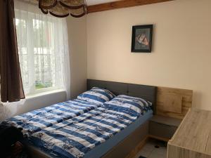 a bed with a blue and white comforter in a bedroom at Bialy domek in Rowy