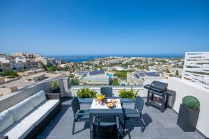 eine Terrasse mit einem Tisch und Stühlen auf dem Balkon in der Unterkunft Artist Terrace Apartments in Mellieħa