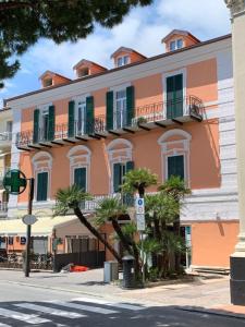 een groot oranje gebouw met palmbomen ervoor bij Le camere della Nonna in Diano Marina
