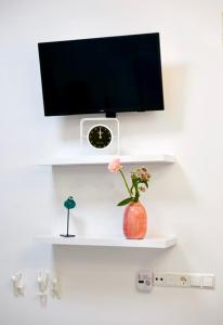 een witte plank met een tv en een vaas met bloemen bij In Den Visser in Dordrecht
