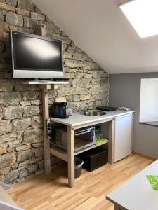 a television on a stand in a room with a stone wall at La Chambre des Bobines in Montigny-sur-lʼAin