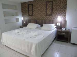 - une chambre avec un lit blanc et des serviettes dans l'établissement Maison Hotel, à Tangará da Serra