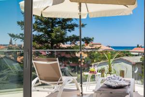 eine Terrasse mit einem Stuhl, einem Sonnenschirm und einem Tisch in der Unterkunft Villa Elena Deluxe mit Whirlpool und POOL am MEER in Fažana