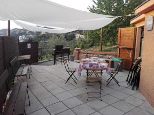 einen Tisch und Stühle auf einer Terrasse unter einem weißen Regenschirm in der Unterkunft Villa Rocca Leivi in Leivi