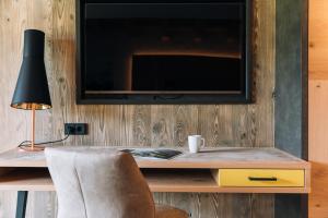 a television on a wall with a desk and a chair at Landhaus Sammer in Tannheim