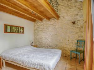 een slaapkamer met een bed en een stenen muur bij Cosy holiday home with garden in Ponet-et-Saint-Auban