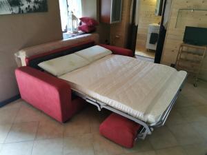a bed in a room with a red couch and a bed sidx sidx at Appartamento Curnet in Balme