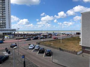 a parking lot next to a beach with cars parked at Odyssee in Zandvoort