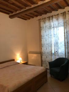 sypialnia z łóżkiem, krzesłem i oknem w obiekcie Residenza Pitigliano w mieście Pitigliano