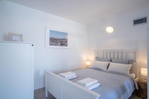 a white bedroom with a bed with two towels on it at A White Cliffside Studio in Pag