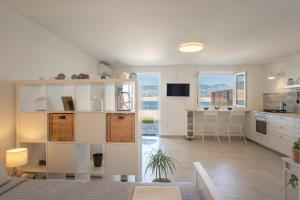 a kitchen and living room with white cabinets and a table at A White Cliffside Studio in Pag