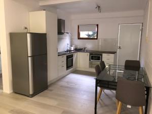 a kitchen with a stainless steel refrigerator and a table at Airlie Getaway Unit 3 in Cannonvale
