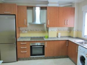 a kitchen with wooden cabinets and a stove top oven at Apartamento Playa de Garrucha in Garrucha