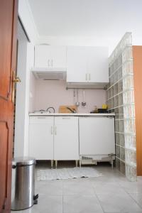 uma cozinha com armários brancos e uma parede de azulejos em Estúdio-Gambelas em Faro