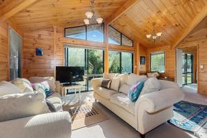 a living room with two couches and a tv at Pearl Retreat - Mangawhai Heads Holiday Home in Mangawhai