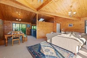 een woonkamer met een bank en een tafel in een hut bij Pearl Retreat - Mangawhai Heads Holiday Home in Mangawhai