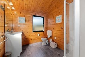 a bathroom with wooden walls and a toilet and a sink at Pearl Retreat - Mangawhai Heads Holiday Home in Mangawhai +14 photos