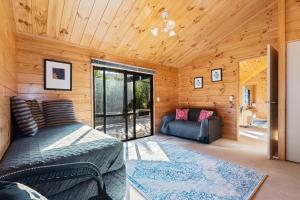 una camera da letto in una baita di tronchi con un letto e un divano di Pearl Retreat - Mangawhai Heads Holiday Home a Mangawhai