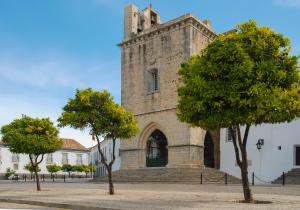 una vieja iglesia con árboles delante de ella en Estúdio-Gambelas en Faro