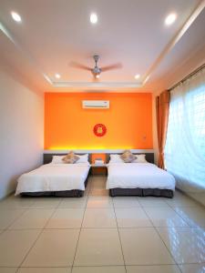 two beds in a room with an orange wall at Warni Villa 13 Whole Or Room in Muar +94 photos