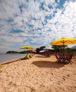 een strand met tafels, stoelen en parasols bij GoodMuning Backpacker in Taliwang