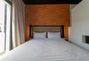 a bedroom with a large white bed with a brick wall at ONOMO Hotel Dakar in Dakar