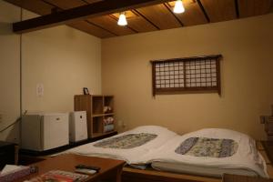 una stanza con due letti, un tavolo e una finestra di Hotel Daiki ad Osaka