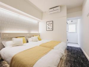 2 camas en una habitación con paredes blancas y almohadas amarillas en 3rd PLACE by HIDEOUT, en Fujisawa