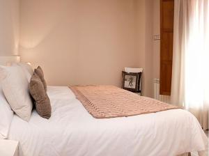 1 cama blanca en un dormitorio con ventana en Tres aguas, en Ezcaray