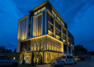Trat City Hotel في ترات: مبنى كبير فيه سيارات تقف امامه