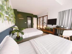 哥打京那巴鲁The Atelier Boutique Hotel的一间有两张床和一台平板电视的酒店房间