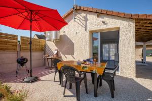 a patio with a table with a red umbrella at La Petite Californie in Saint-Illiers-la-Ville