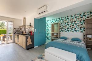 a bedroom with a blue bed and a kitchen at La Petite Californie in Saint-Illiers-la-Ville