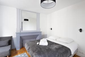 1 dormitorio con cama, silla y espejo en Le Dinanais - Cocon dans l'Intra Muros, en Saint-Malo
