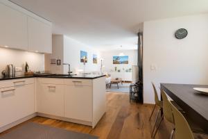 eine Küche mit weißen Schränken und ein Esszimmer in der Unterkunft Montela Hotel & Resort - Apartments in Saas-Grund