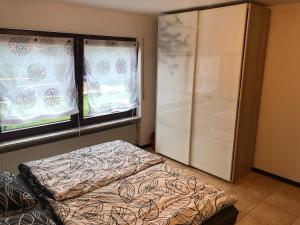 1 dormitorio con 1 cama y 2 ventanas con cortinas en Ferienwohnung Janson-2 en Wiesenbach