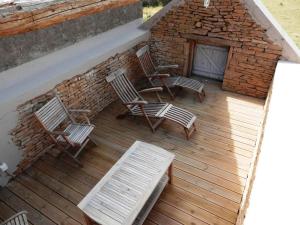 three chairs and a table on a wooden deck at La Maison du vigneron in Ameugny